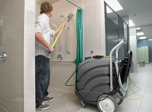 Un empleado limpiando una ducha con el limpiador para todas las superficies ASC-15 
